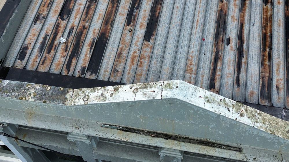 Metal roof sheeting dented and rusting through its coating, found during a defect investigation inspection in Richmond